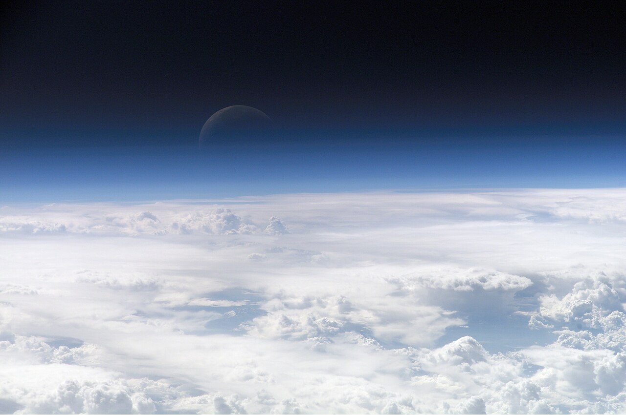 Illustrative stock photograph of Earth’s atmosphere and a crescent Moon taken from the International Space Station in 2006.