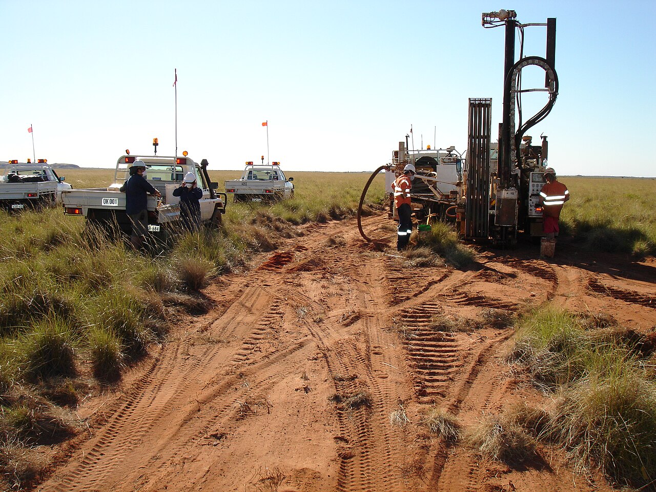 A land drill rig on red earth, the surface kit around deep holes