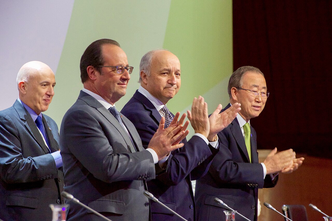 François Hollande, Laurent Fabius and Ban Ki-moon applaud on the COP21 stage after the Paris Agreement was adopted