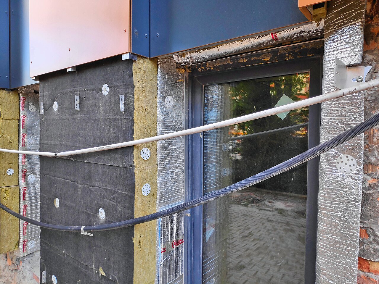 Exterior wall of a store wrapped in mineral-wool insulation during a thermal retrofit