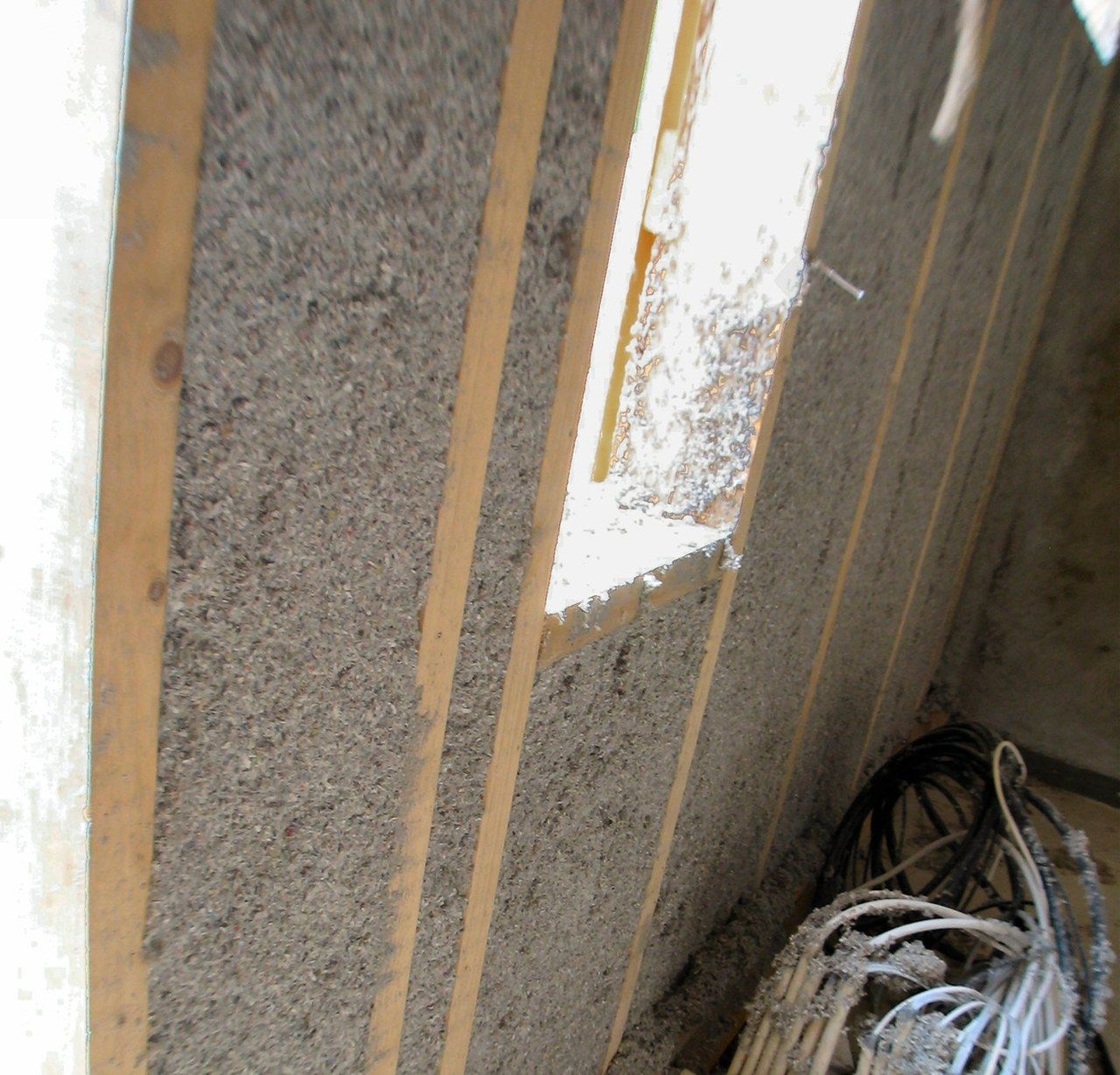 Sprayed paper-based cellulose insulation filling the cavities of a timber wall frame.
