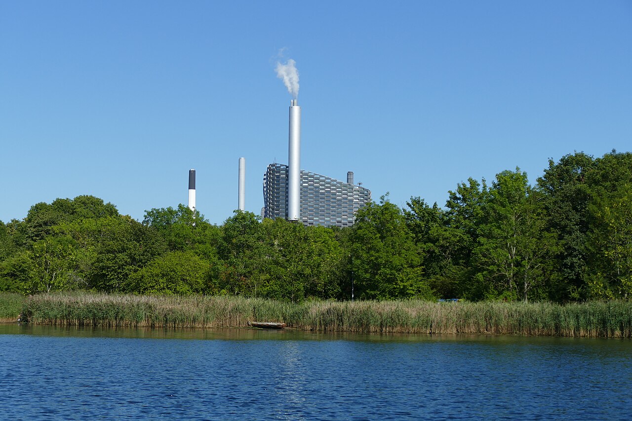 Copenhagen’s Amager Bakke waste-to-energy plant across water, with steam from the stack