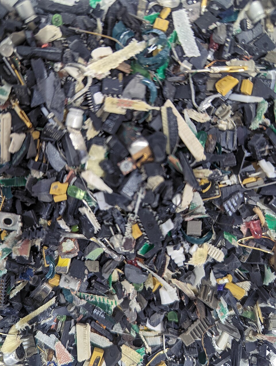 Shredded circuit boards and electronic components sorted for material recovery, shown as an exhibit in Tsukuba, Japan.