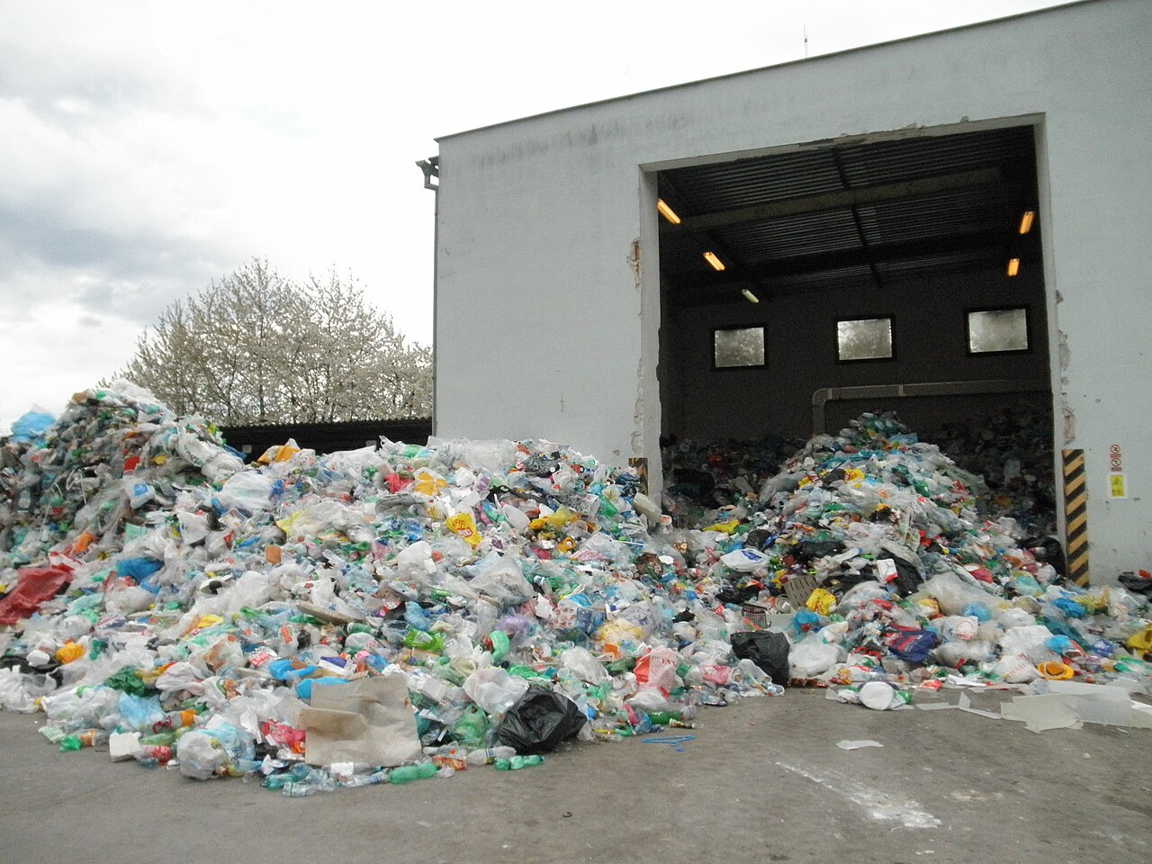 Piles of mixed plastic bottles on the apron of a material recovery facility