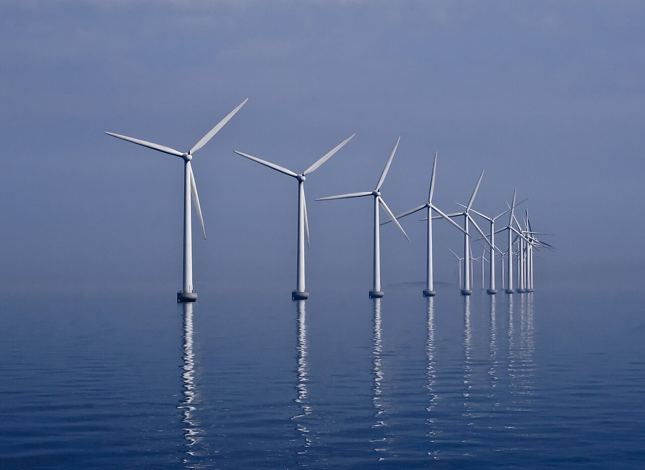A curved row of offshore wind turbines at Middelgrunden in the Øresund, with Copenhagen on the horizon