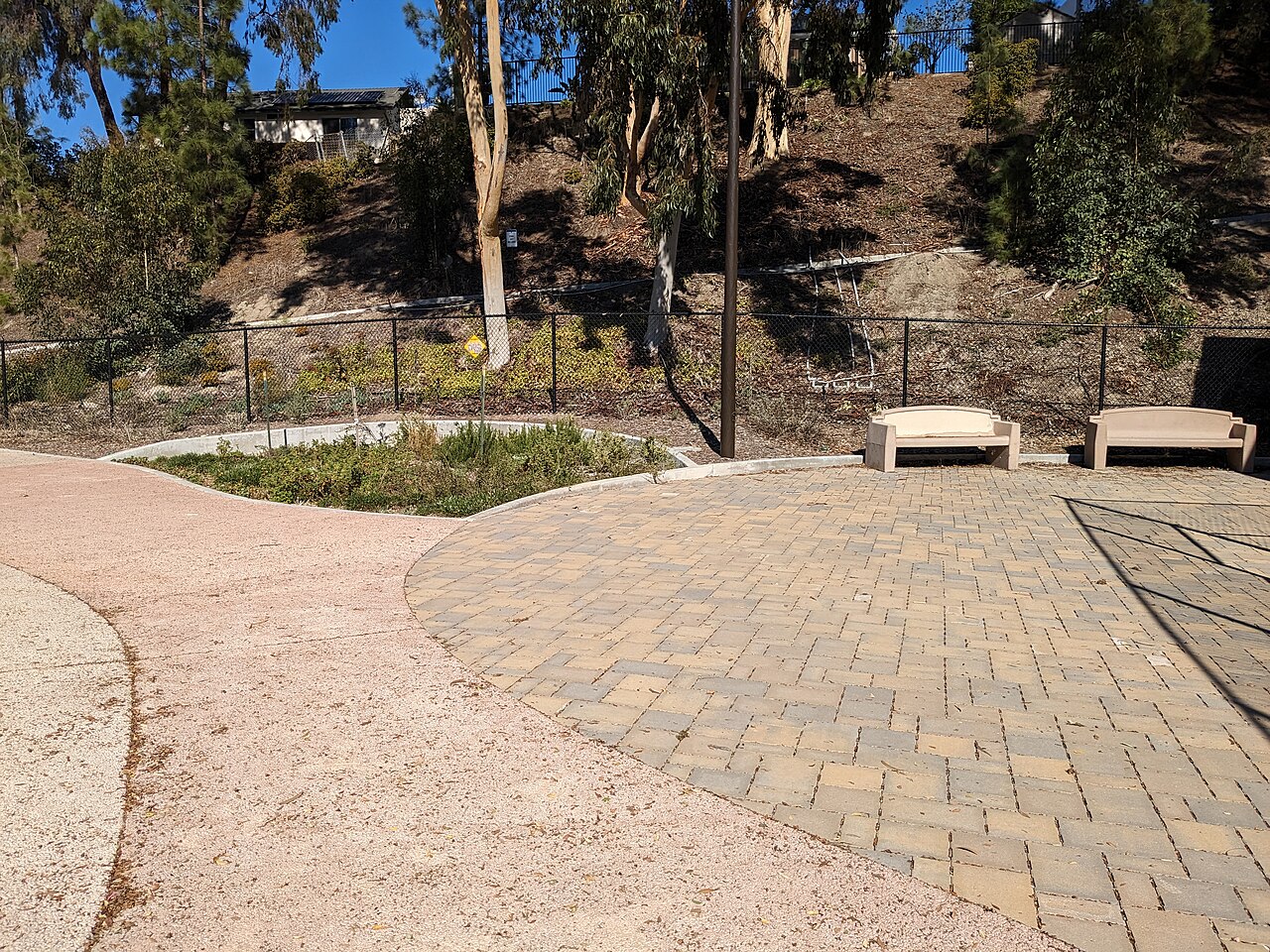 Interlocking permeable pavers beside a sunken rain garden in a public park