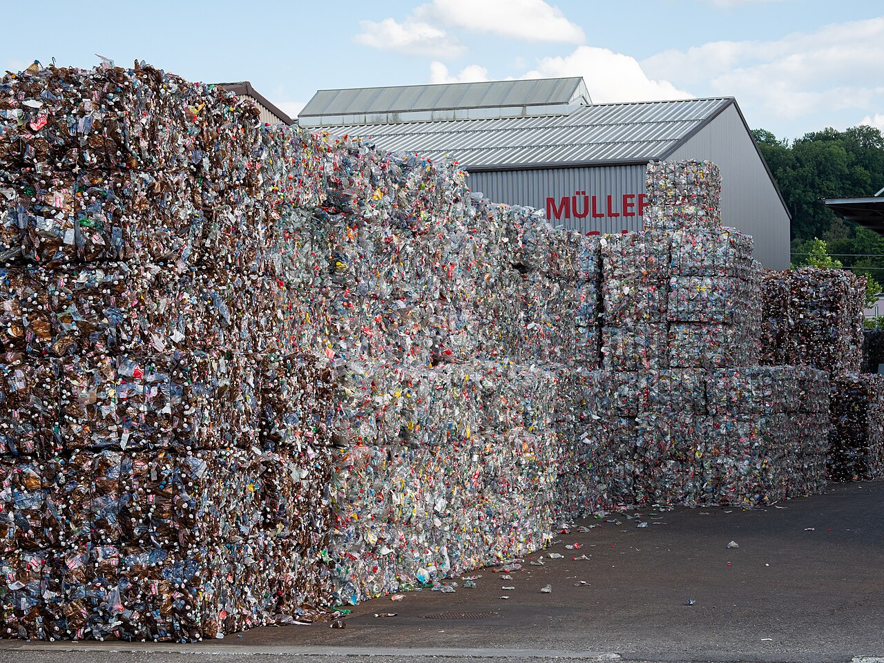 Stacked bales of compressed plastic drink bottles in the yard of a recycling plant