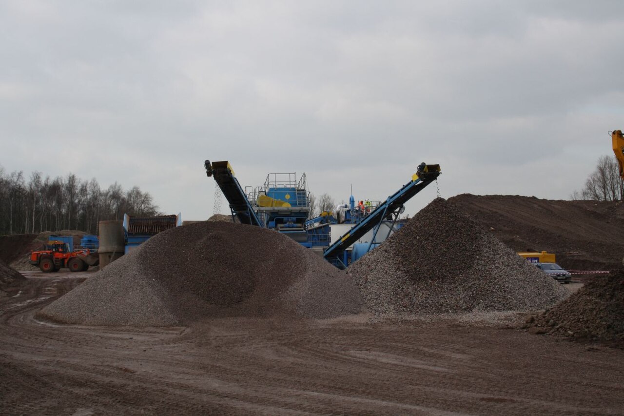 Open-air stockpiles of crushed recycled aggregate beside a materials yard