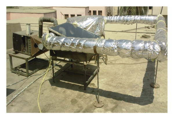 A rooftop solar still in Cairo with an insulated duct loop around a dark evaporator box
