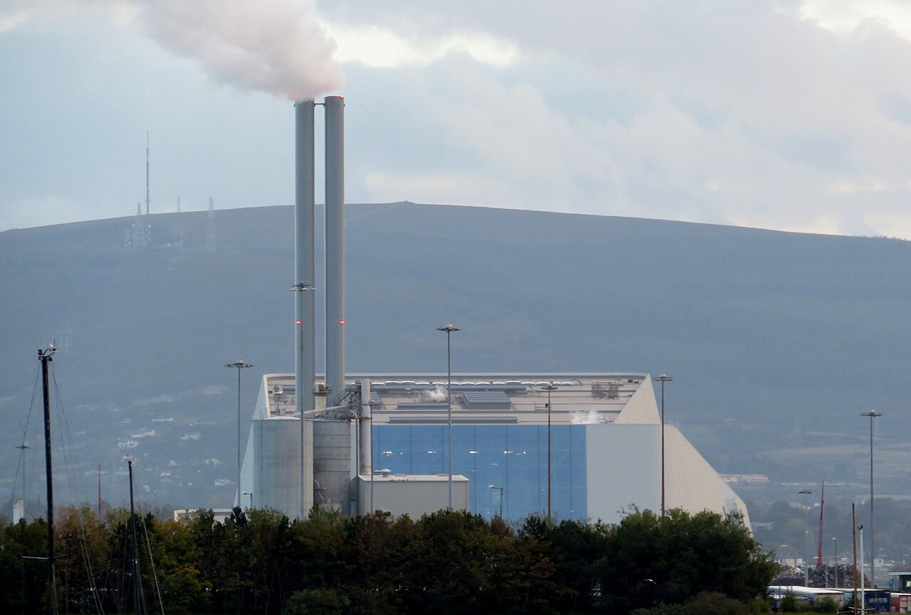 The Dublin Waste-to-Energy plant: a white hall and twin stacks with a hill behind